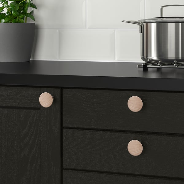 Black cabinet with wooden knobs and plant.