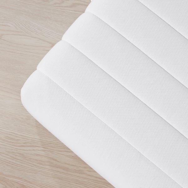Close-up of ÅNNFJÄLLET mattress on wooden floor, showcasing its firm, textured surface and comfortable padding.