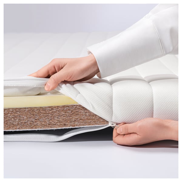 Person showing layers of white ÅNNFJÄLLET mattress.