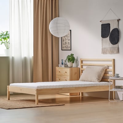 Modern bedroom with ÅNNFJÄLLET bed, bedside table, lantern, and decor. Clean, minimalist aesthetic.