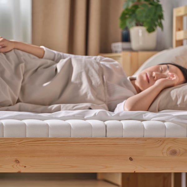 A person sleeps peacefully on a firm ÅNNFJÄLLET mattress, which provides support and comfort for a restful nights sleep.