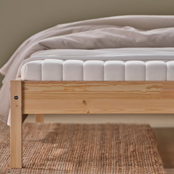 Bed with firm natural coir mattress and foam top, sectioned for airflow, on wooden base.