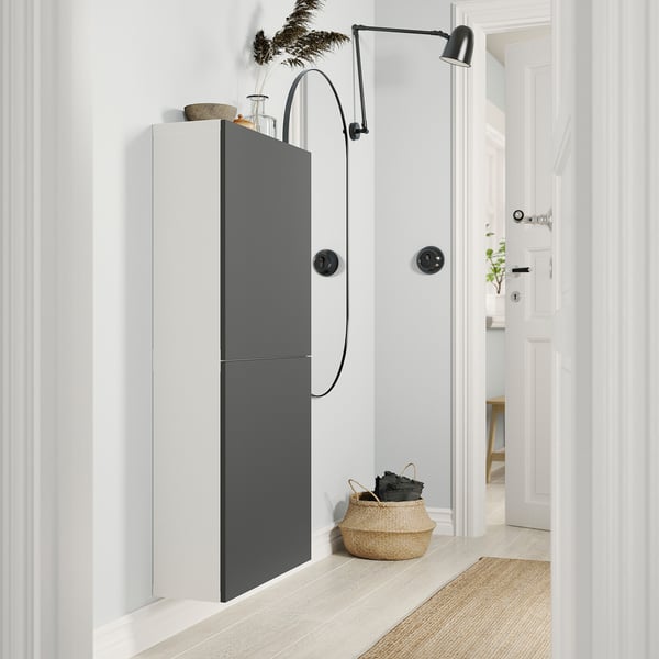 Modern entryway with BESTÅ storage unit; black and white cabinet, woven basket, round mirror, wall lamp.