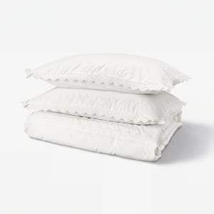 Stacked white lace-trimmed cotton bedding: duvet cover & pillowcases.