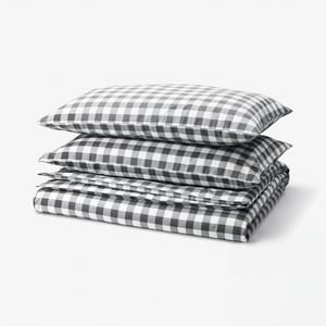 Stacked black and white gingham check bedding set. Includes duvet and two pillowcases, made from 100% organic cotton.