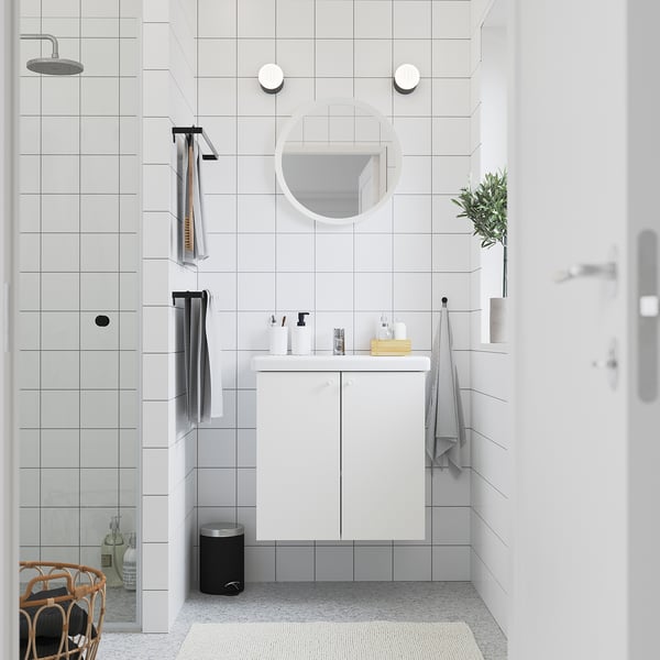 Modern white bathroom with ENHET vanity, mirror, glass shower, & plant.