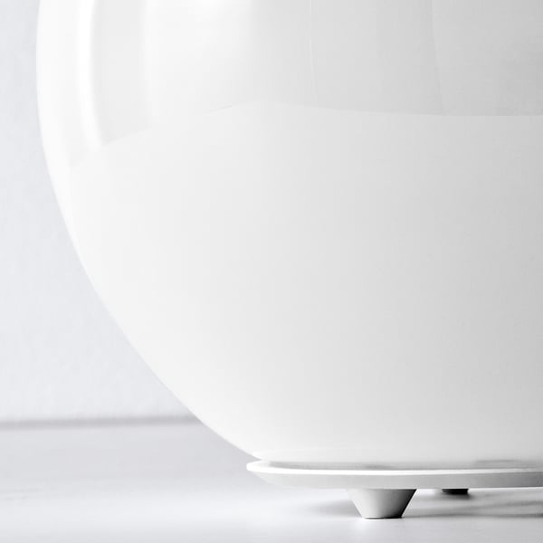 Large white globe lamp with sleek base, casting soft light, black and white.