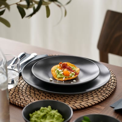 Modern, round black plate holding gourmet dish, showcasing practical and stylish design.