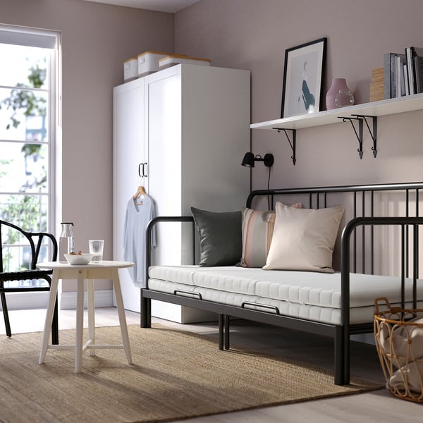 Minimalist bedroom with FYRESDAL day-bed, colourful pillows, white wardrobe, and natural light.