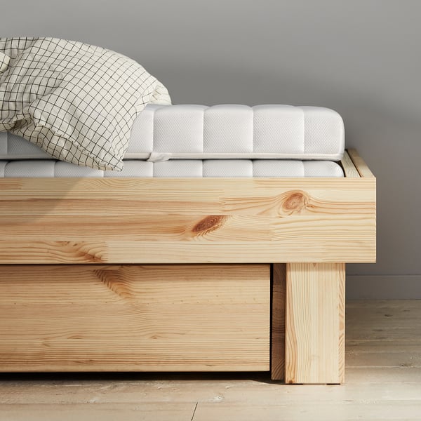 Minimalist bed with natural wooden base and white mattress, showcasing quality craftsmanship and simple elegance.