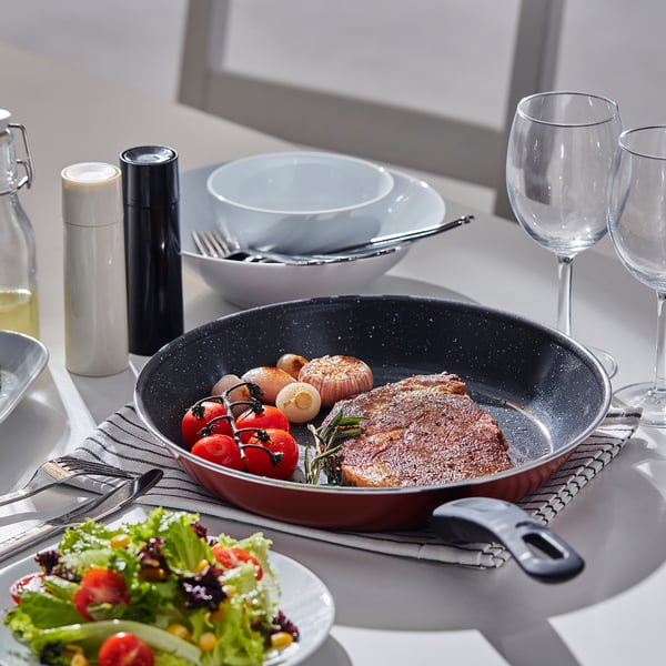 Dining table with skillet, vegetables, bowls, & glasses.