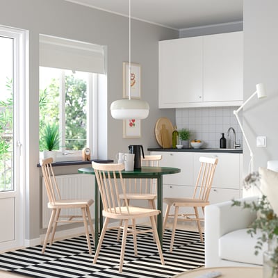 Modern kitchen with green table, wooden chairs, pendant lamp, and large window.