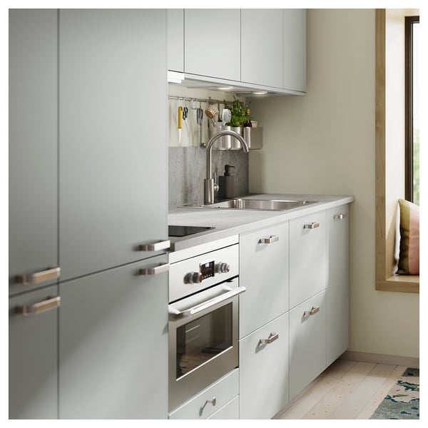 Modern kitchen with light grey cabinets, stainless steel appliances, and sleek metallic handles. A clean and minimalist design with wooden floors.