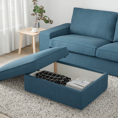 Blue sofa with open storage ottoman holding magazines and remote.