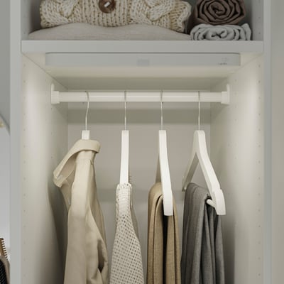 Closet with KÖLVATTEN light, hanging clothes, folded blankets, neat organisation.