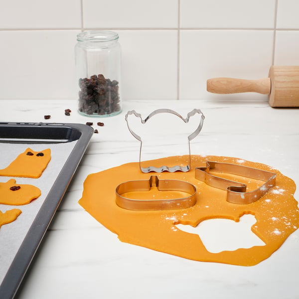 Baking tools: 3 cookie cutters on dough - cat, ghost, pumpkin.