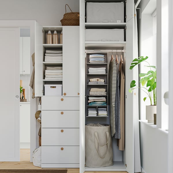 Well-organized closet with shelves, drawers, and hanging space, featuring light-colored decor and neatly folded clothes.