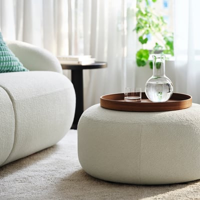 Living room with LILLESÄTER pouffe, tray of drinks, near couch and plant.