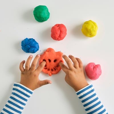 Childrens hands playing with colourful modelling dough.