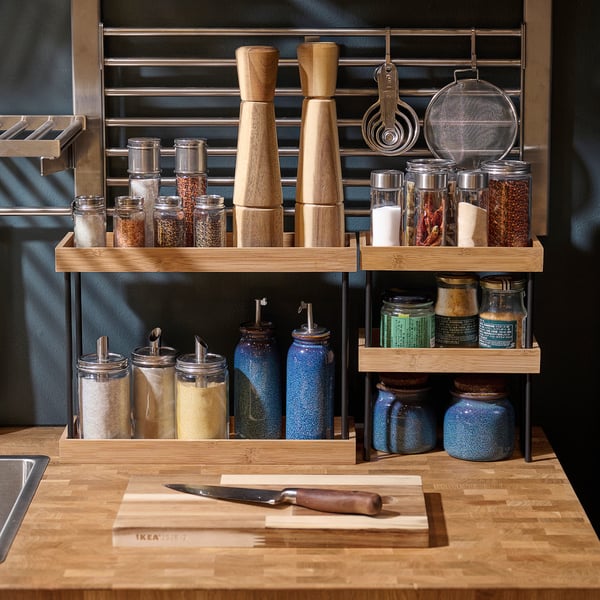 Organised kitchen counter with NÅLBLECKA bamboo storage. Includes jars, spice mills, and containers for neat display and easy access.