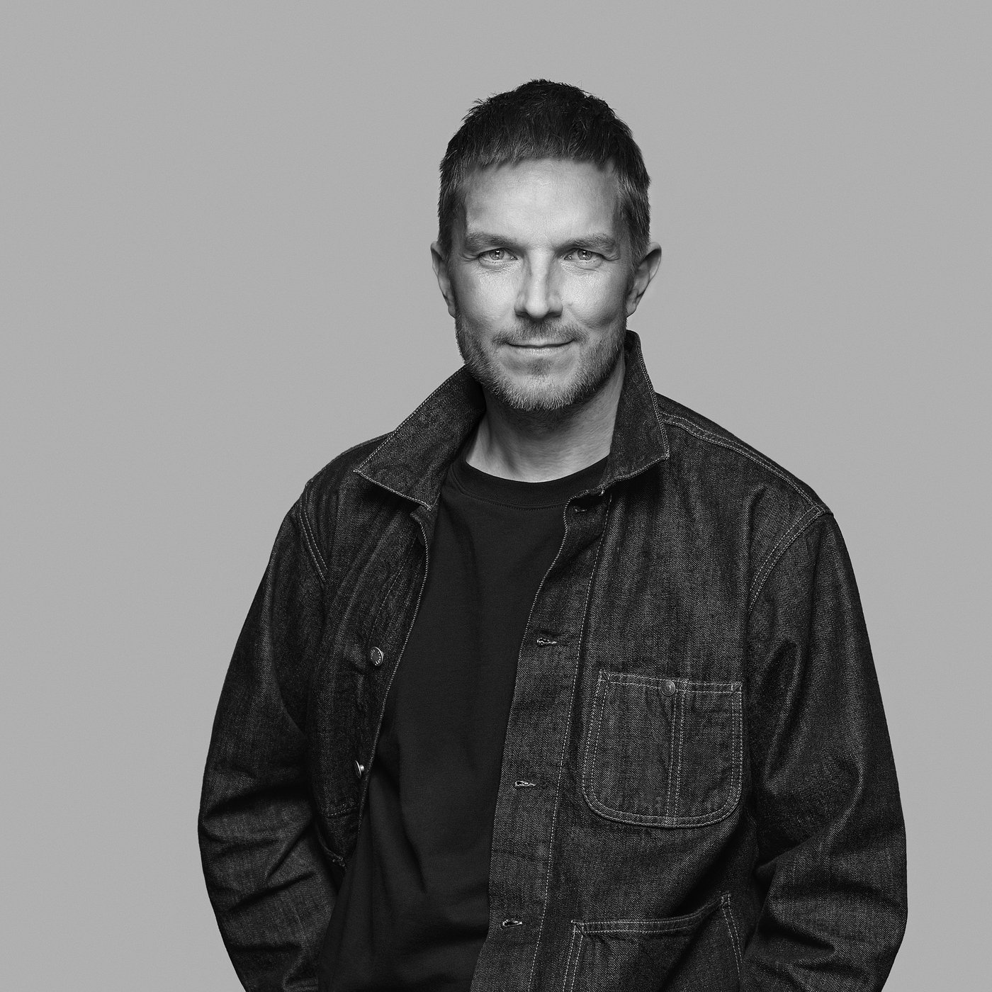 Black and white portrait of Henrik Preutz wearing a shirt and jacket, with short hair.