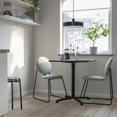 Modern kitchen nook with black metal STENSELE table and green cushioned chairs, perfect for small spaces.
