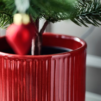 Vibrant red textured plant pot with a glossy glaze, holding a green plant. High-quality craftsmanship is evident in its smooth finish.
