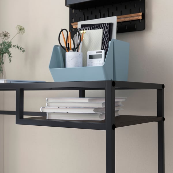 Black metal desk with glass shelf, organising blue bins and papers.