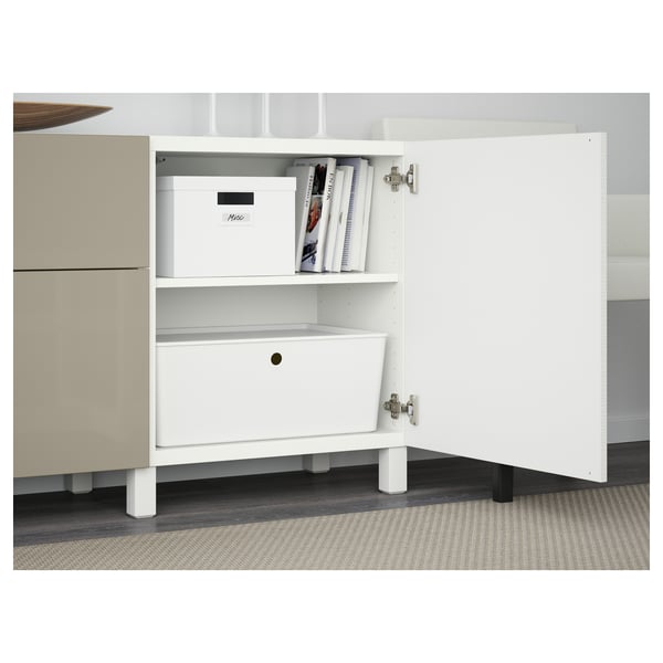 White storage unit with one open drawer and shelf, holding white boxed items and books.