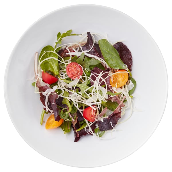Farfurie albă cu salată proaspătă, roșii cherry colorate, brânză mărunțită și verdeață mixtă.