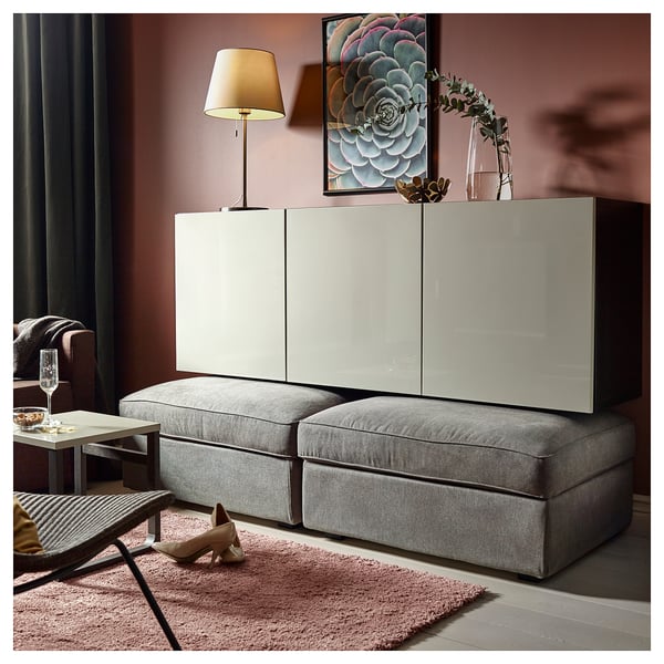 Modern living room with grey BESTÅ storage, white doors, adjustable shelves, soft closing hinges. Decor includes lamp, art, and flowers.