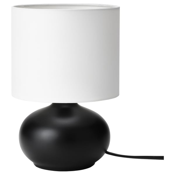Modern desk lamp, TVÄRFOT. Black, oval stoneware base. White cylindrical shade. Simple, stylish design.