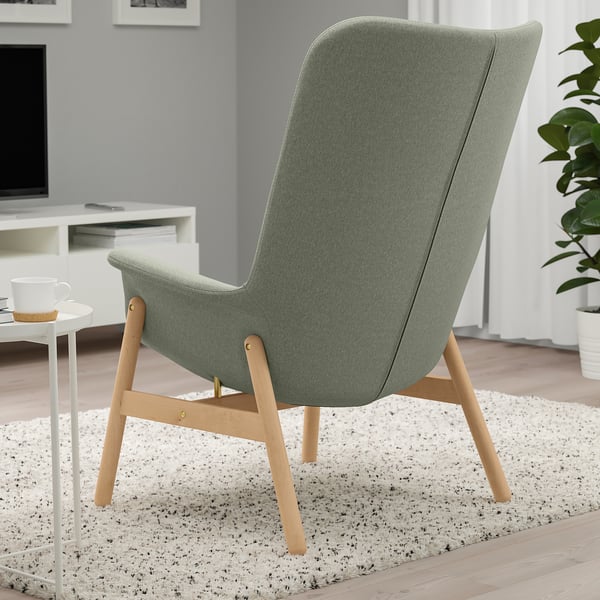 Green VEDBO armchair with high back for privacy, wooden legs, on a speckled rug in a cozy room.