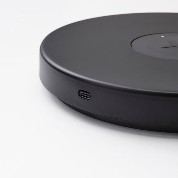 Round black wireless charging pad with usb-c port, sleek matte finish.