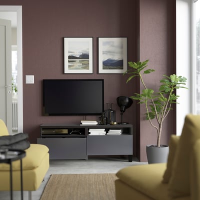 Modern living room with purple walls, yellow chairs, grey tv stand holding a flat screen, and art pieces.