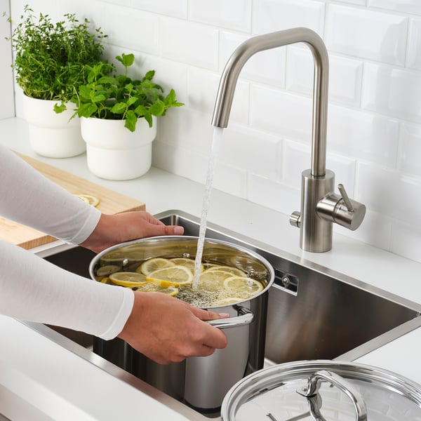 Pouring water with lemon in modern kitchen.