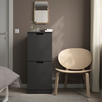 A NORDLI black chest with two drawers between a mirror and chair.