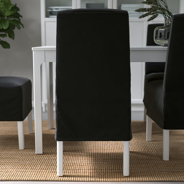 Chairs with black velvet-covered backs and white metal legs around a table.