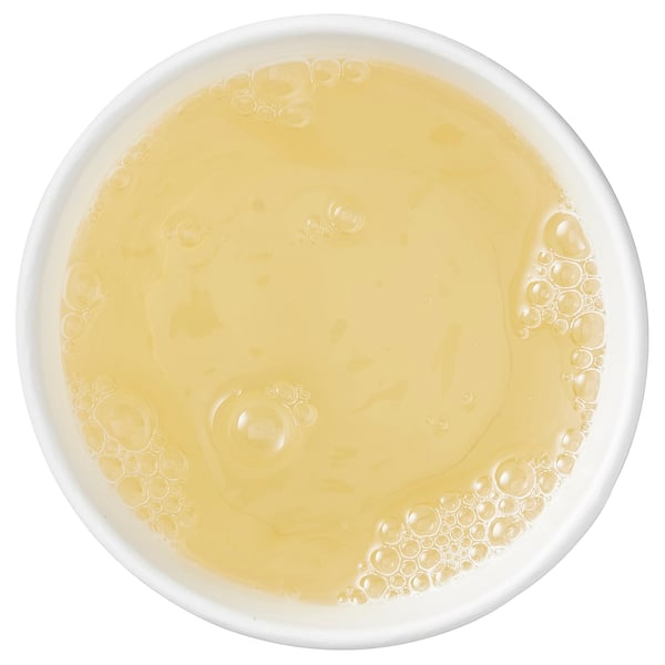 Top view of a bowl with yellow liquid, possibly soup or sauce.