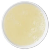 Top view of a white bowl filled with creamy yellow liquid, likely a beverage or sauce.