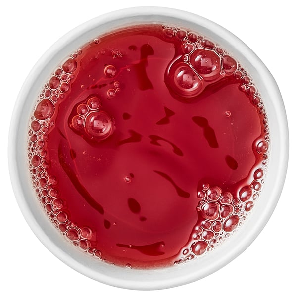 Top view of a bowl with dark red liquid, likely beverage; simple and vibrant.