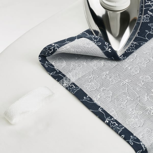 Железо, парящее над шторой TRYSTÄVMAL, с фильтрующим свет узором в виде цветов.