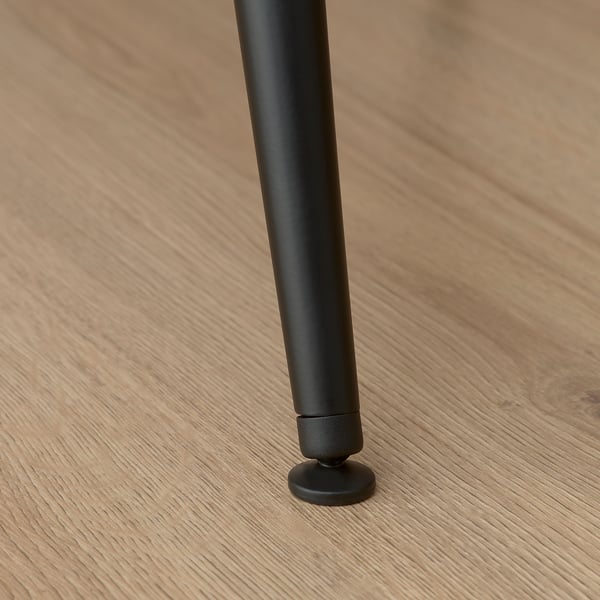 Black chair leg with adjustable foot on wooden floor, showcasing sturdy and stable design.