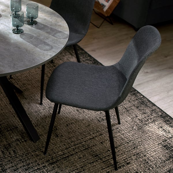 Dark gray GALLERUD chair, minimalist, padded with recycled materials, fits under round table.