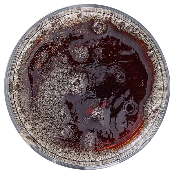 Clear glass filled with dark, bubbly beverage, likely soda. Top view shows effervescence.