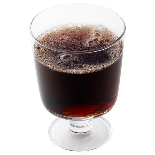Glass filled with dark drink, possibly cola, bubbly top, on white surface.