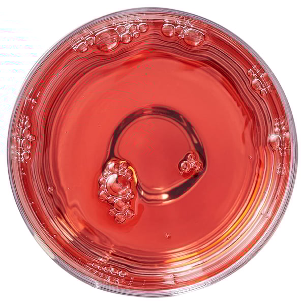 A glass filled with bubbly, reddish liquid, possibly a beverage.