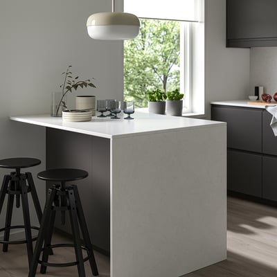 Minimalist kitchen with recycled glass counter, black stools, pendant light, and gray cabinets.