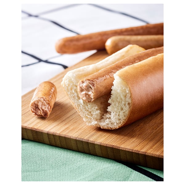 Hot-dog shaped plant-based food on a wooden board. Golden-brown exterior, soft interior. Placed on green cloth.