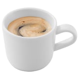 A white ceramic mug filled with frothy coffee; a simple and comforting beverage.